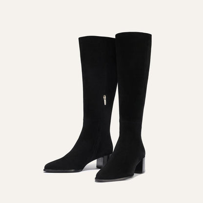 The Uptown Boot - Black Suede by margaux-development: black knee-high suede boots with low block heels and side zippers, shown against a plain light background.