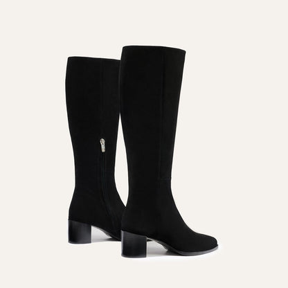 The Uptown Boot - Black Suede by margaux-development: black knee-high boots with low block heels and side zippers, shown against a plain light background.