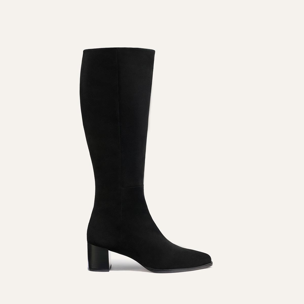 The Uptown Boot - Black Suede by margaux-development is a black knee-high boot with a block heel, crafted from suede-like material and displayed in profile against a light beige background.