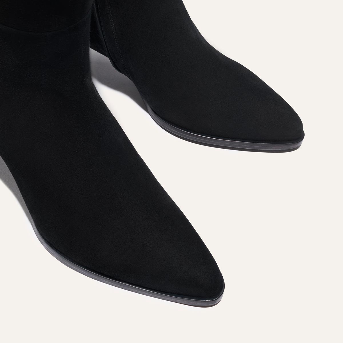 Close-up of The Uptown Boot in black suede by margaux-development, featuring a pointed toe and shown on a light background.