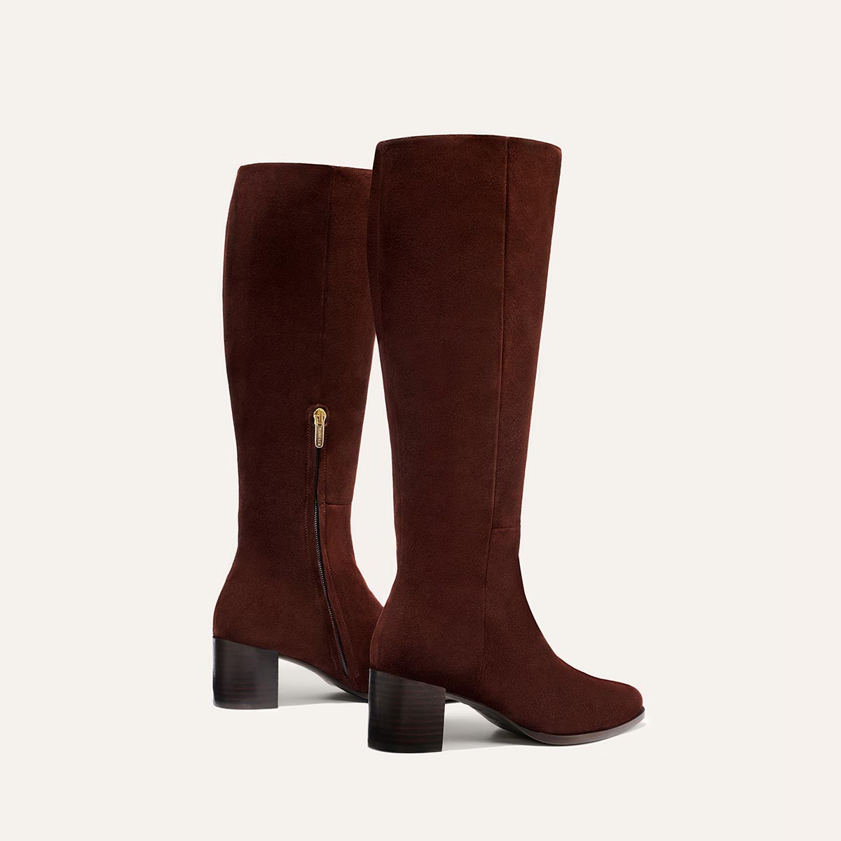 The Uptown Boot - Chocolate Suede by margaux-development: knee-high brown suede boots with block heels and side zippers, shown against a plain, light background—an elevated twist on the classic ankle boot.