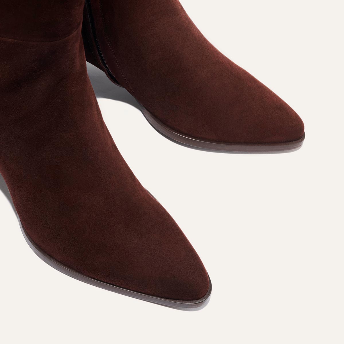 Close-up of The Uptown Boot by margaux-development, a bestselling ankle boot in chocolate suede with a pointed toe, shown against a light background.