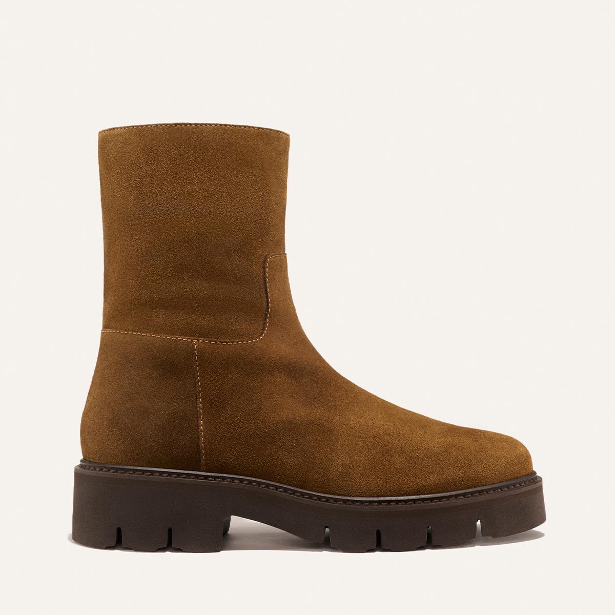 The Wells Boot in Cedar Suede by Margaux features a brown suede upper with a chunky black rubber sole, side stitching detail, and a rounded toe, shown on a plain light background.