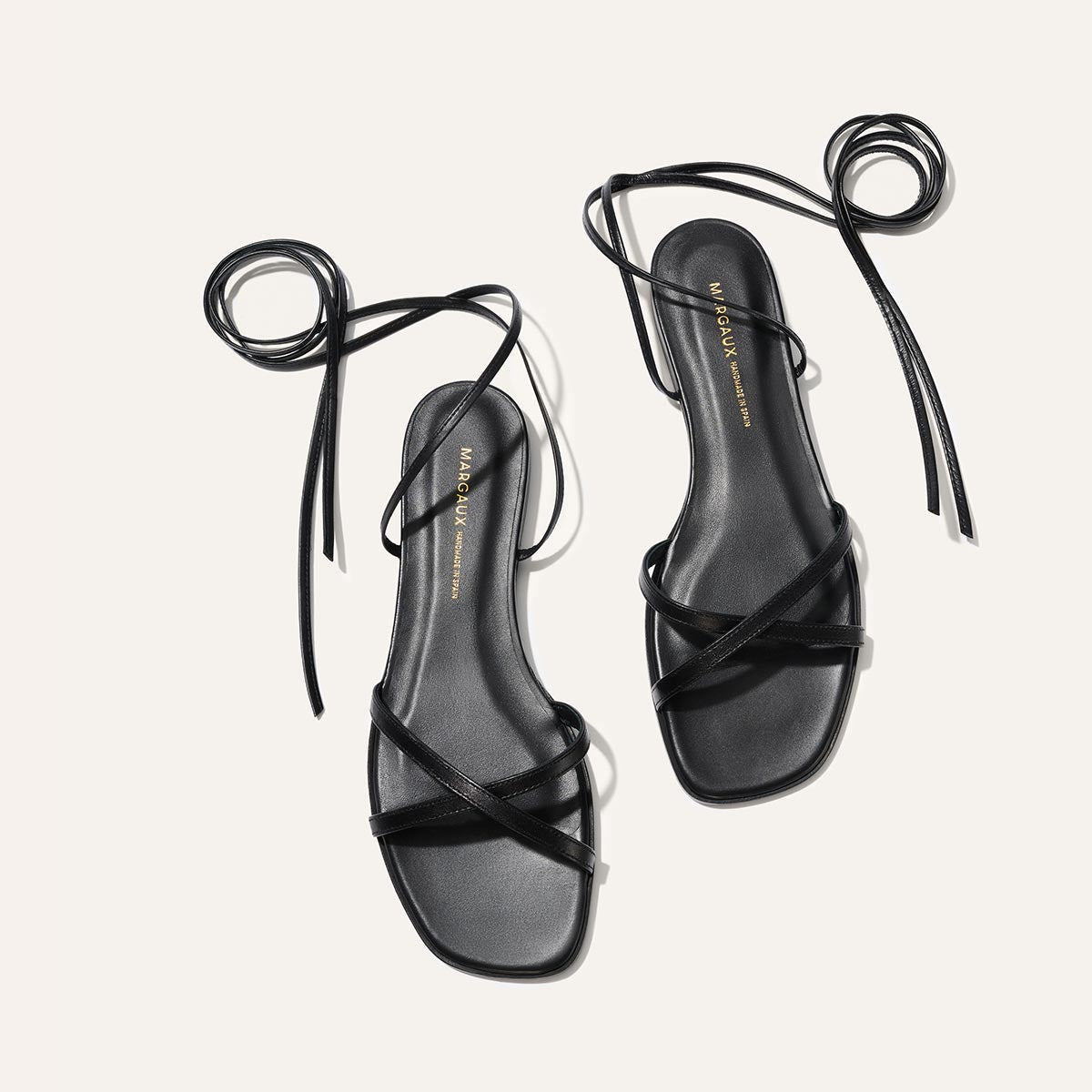 Black strappy sandals on a light gray background