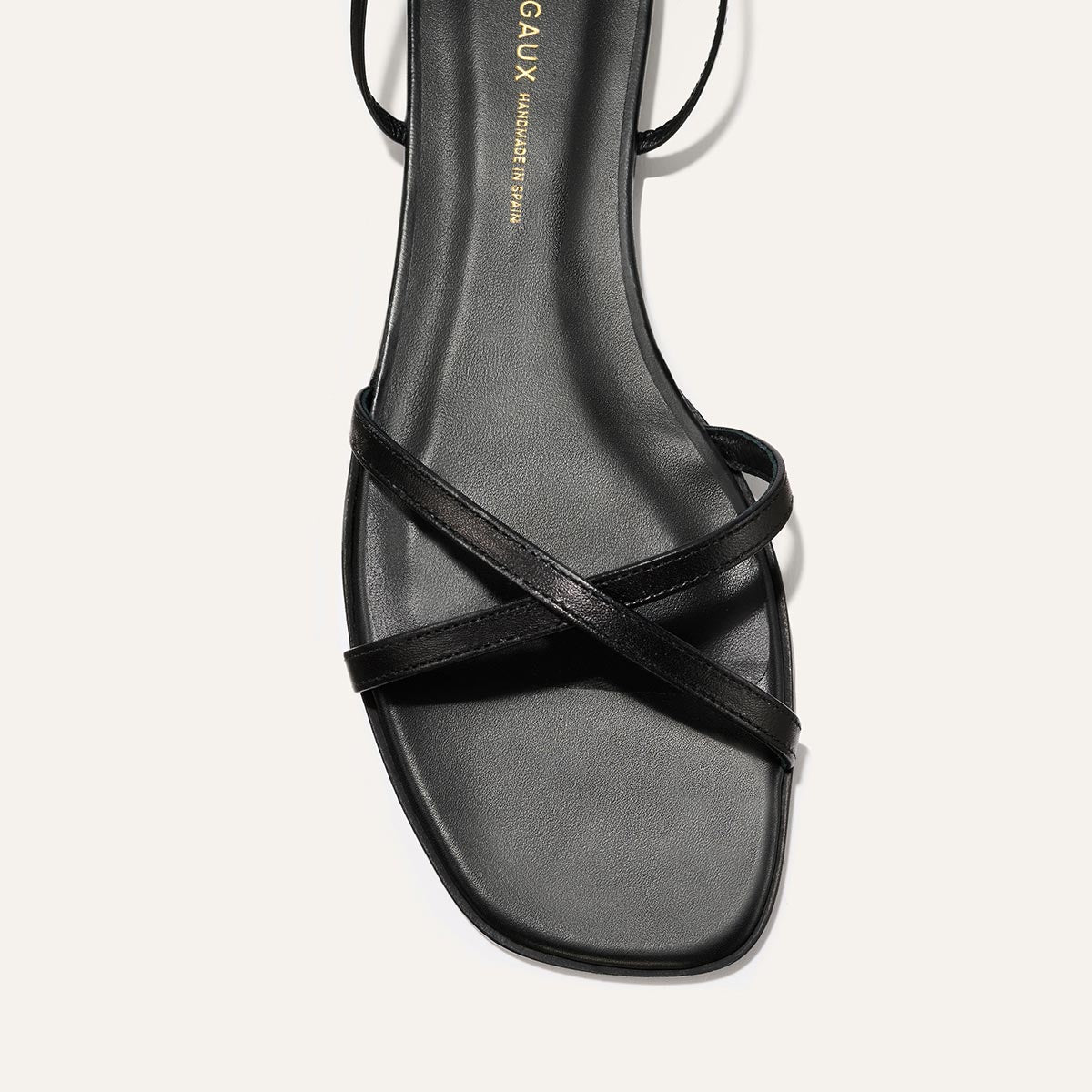 Black sandal with criss-cross straps on a white background