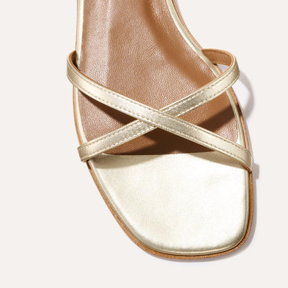 A close-up of Margaux’s The Wrap Sandal in Champagne Nappa, featuring a square toe, two thin crisscrossing straps, and a tan insole—minimal and elegant for effortless summer versatility.