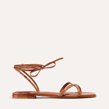 A saddle brown leather sandal with an open toe and wrap around the ankle.