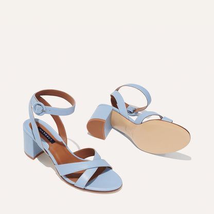 The City Sandal - Fog Nappa by margaux-development: light blue open-toe block heeled sandals with ankle straps and buckle closures. One sandal stands upright, the other lies on its side showing the cushioned insole for comfort.