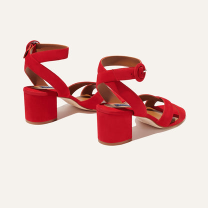 The City Sandal - Poppy Suede by margaux-development features red suede, ankle straps with round buckles, cushioned insoles for comfort, and round block heels. The crossover straps are displayed on a light background.
