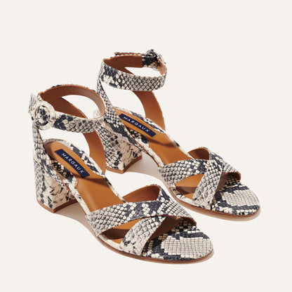 The City Sandal - Natural Python Embossed by margaux-development features a snake print, crisscross front and ankle buckle straps, block heels, and a cushioned tan insole with a blue Margaux label for comfort.