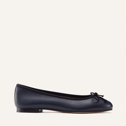 The Demi in Navy Nappa with black trim, a comfortable ballet flat with a rounded toe and adjustable cord bow detail.