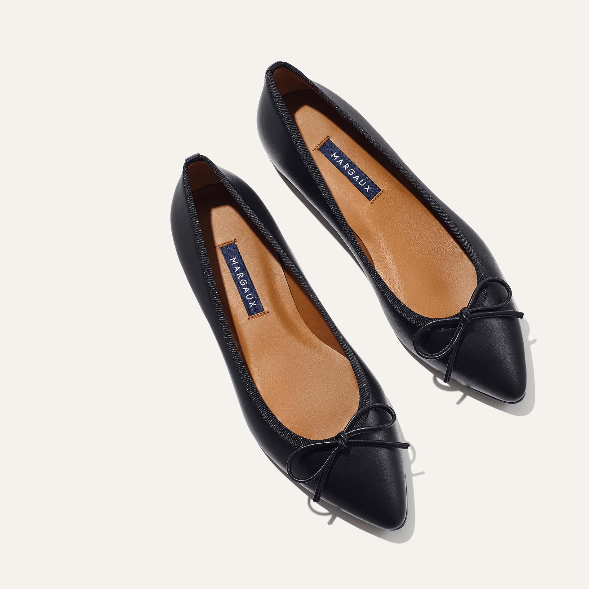 The Pointe in Black Nappa, a classic and comfortable ballet flat featuring a refined pointed toe design and decorative bow. 