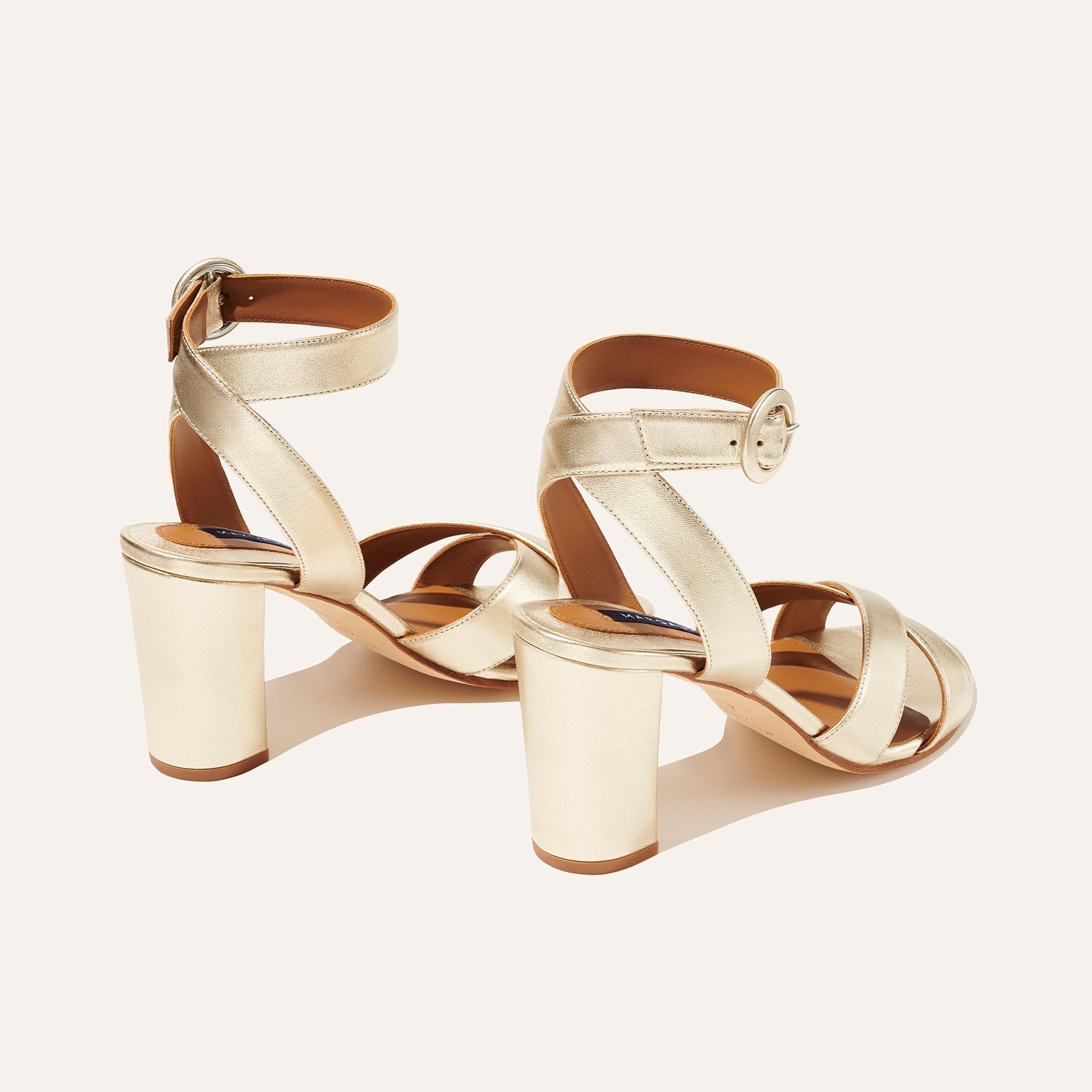 The Uptown Sandal - Champagne by margaux-development: gold block heel sandals with ankle straps, round buckles, and crisscross toe straps—crafted for all-day comfort and style against a light background.