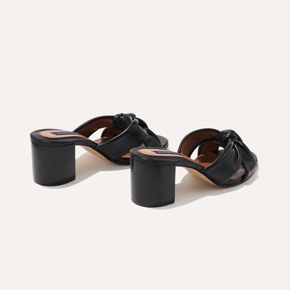 The Carmine Mule in Black Nappa, a slide-on heel featuring a plush knot detail and comfortable 2.5-inch block heel