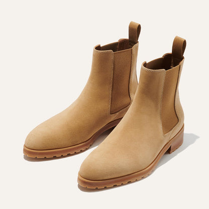 A pair of tan suede Chelsea boots with elastic side panels, pull tabs at the back, and light brown rubber soles, displayed on a plain light background.