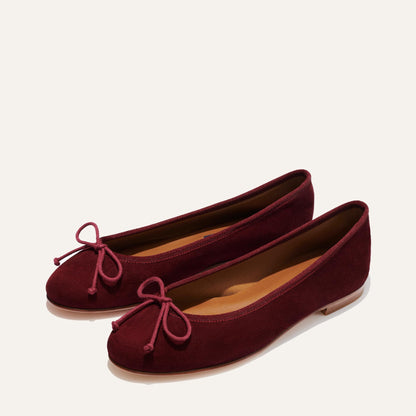 The Demi - Mulberry Suede ballet flats by margaux-development feature burgundy suede, round toes, front bow details, and low flat heels. Handmade in Spain and photographed against a plain light background.