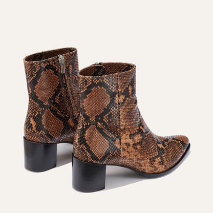 The Downtown Boot First Edition in Espresso Python Embossed by Margaux features a western-inspired, ankle-high brown and black snakeskin pattern, chunky black heels, and side zippers, displayed on a plain light background.
