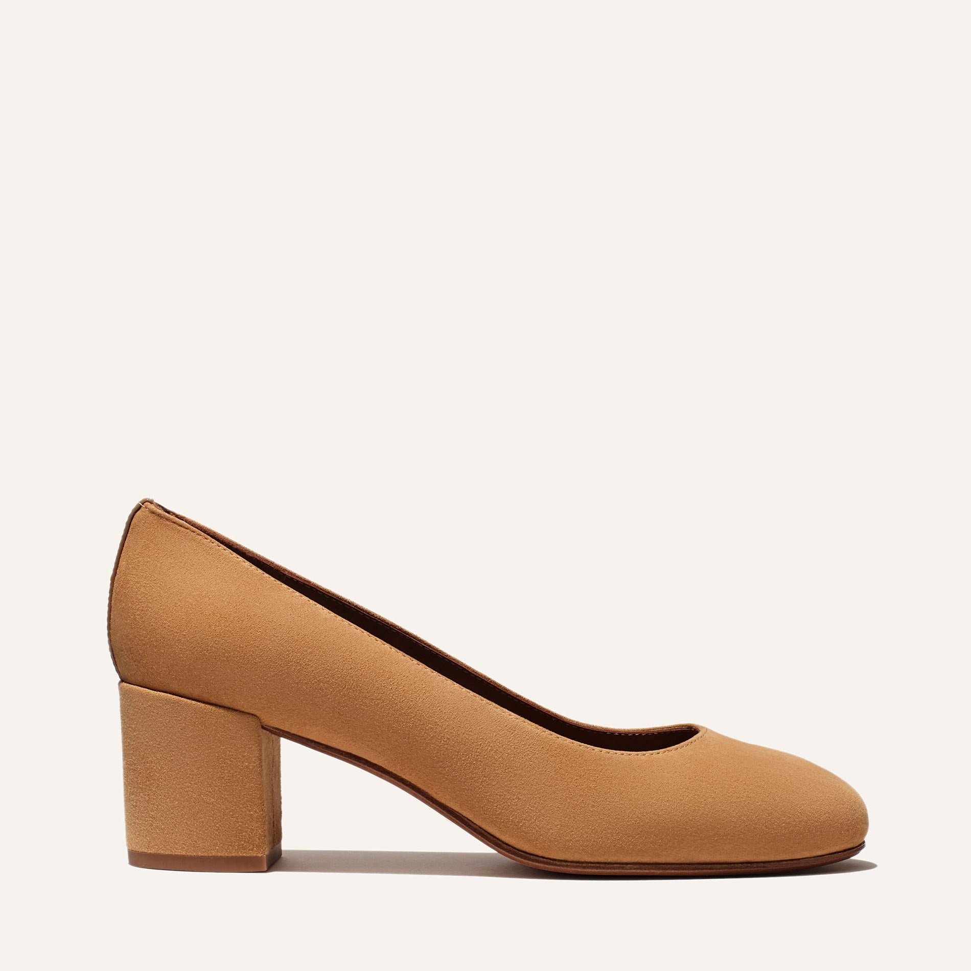 The Heel - Cacao Suede by Margaux is an elegant tan suede pump featuring a rounded toe and medium block heel, displayed in side profile against a plain, light background.