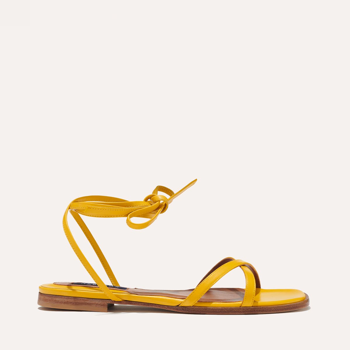 Margaux's classic strappy Wrap Sandal with ankle ties, made in Spain from soft, sunflower yellow Italian suede